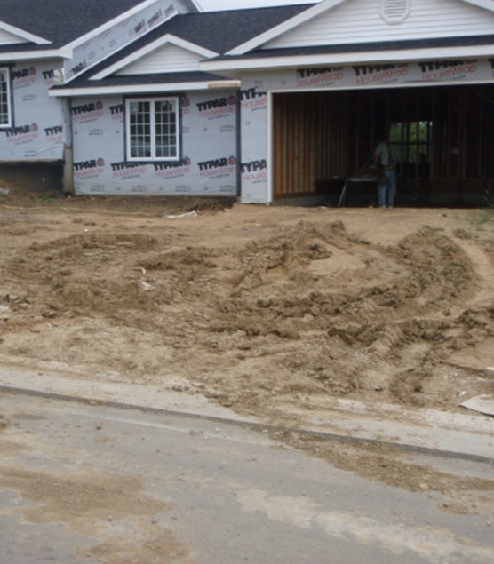 Photo of a partially constructed single family home. Dirt has been tracked from the home lot into the roadway.